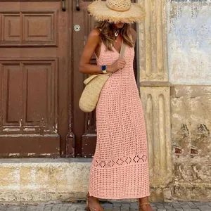 Model wearing a pink crochet hollow-out long beach dress against a vintage wooden door