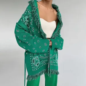 Détail du cardigan bohème en tricot vert avec motif paisley blanc et franges