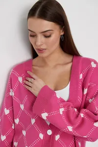 Detailed close-up of pink knitted cardigan featuring white heart jacquard pattern and buttons