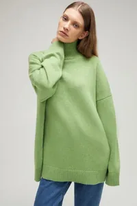Close-up detail showing the texture of a women's oversized lime green turtleneck knit sweater