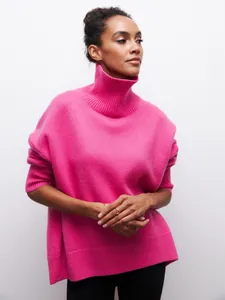 Détail d'un pull à col roulé rose surdimensionné avec une texture tricotée.