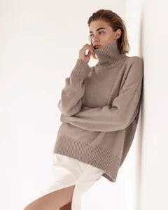 Detailed view of a thick taupe turtleneck sweater featuring a soft and cozy knit texture