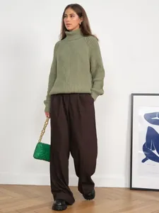 Full view of a stylish green chunky knit turtleneck sweater paired with brown wide-leg pants.