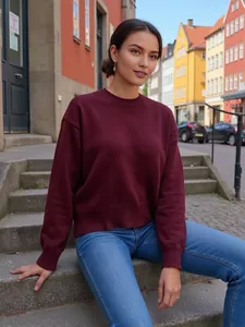 Femme portant un pull en maille bordeaux ample à col rond dans un décor urbain
