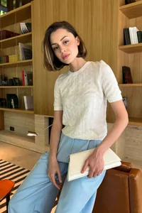 Model wearing white short-sleeved knit sweater with textured diamond pattern