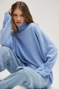 Detail of loose-fitting light blue turtleneck sweater in soft knit fabric