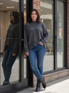 Vue détaillée d'un pull en maille gris oversize pour femme avec un jean et des bottes.