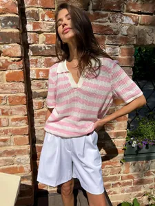 Fashionable pink and white striped knit polo shirt styled on a model by a wall