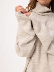 Detail view of a cozy beige turtleneck sweater with soft knit texture and loose fit