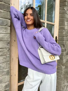 Lifestyle view of a woman wearing an oversized purple crewneck knit sweater outdoors