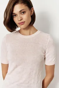 Close-up detail of a light pink short sleeve knit sweater with intricate patterns