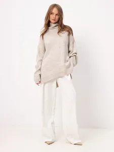 Model wearing an oversized beige turtleneck sweater and white wide-leg pants