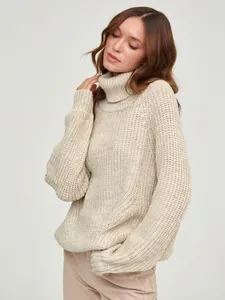 Close-up detail of a women's chunky knit turtleneck sweater in a cozy beige loose-fit style
