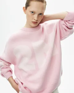 Nahaufnahme eines rosafarbenen Oversize-Strickpullovers mit großen weißen Grafikzahlen