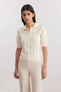 Model wearing cream short-sleeve knit polo shirt with intricate pointelle pattern