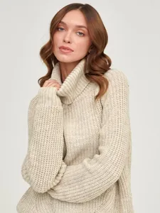 Close-up of beige oversized turtleneck knit sweater with thick ribbed texture