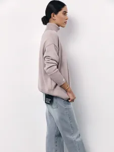 Women's loose turtleneck mauve knit sweater with side profile view in light blue jeans