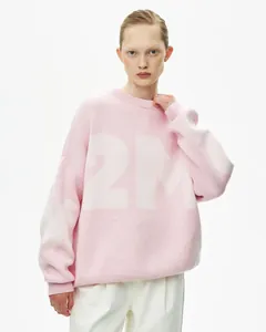 Detail des übergroßen rosa Strickpullovers mit schickem weißem Buchstaben-Jacquard-Design