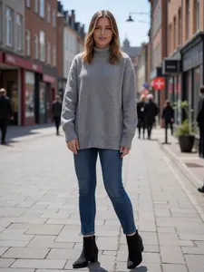 Frau trägt einen grauen Oversize-Rollkragenpullover und blaue Jeans in einer Stadtstraße.