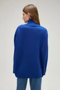 Back view of a woman wearing a comfortable royal blue oversized mock neck knit sweater