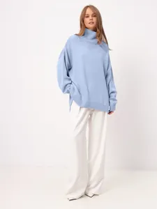 Oversized light blue turtleneck knit sweater with side slits and wide-leg white pants