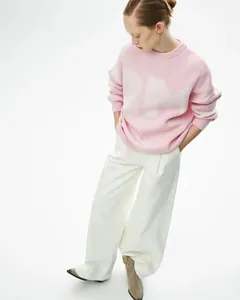 Model trägt rosa Strickpullover mit Rundhalsausschnitt und großen weißen RM-Buchstaben