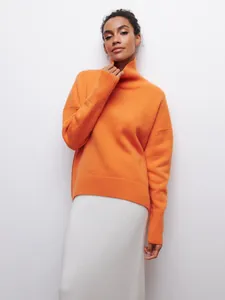 Vue détaillée d'un pull à col roulé orange surdimensionné avec texture côtelée.