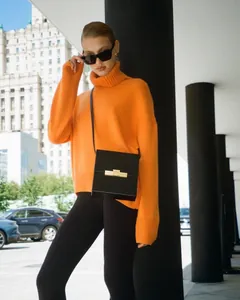 Chic orange turtleneck knit sweater and minimalist black crossbody bag in city setting