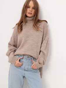 Detailed shot of a loose beige turtleneck sweater with soft and delicate knitted texture