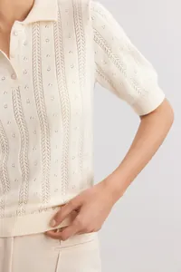 Close-up detail of cream pointelle knit polo shirt showing delicate vertical patterns