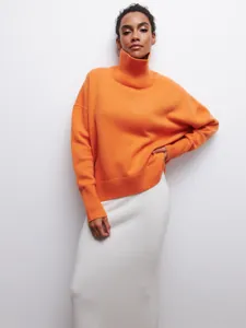 Détail d'un pull à col roulé orange vif pour femme avec poignets et ourlet côtelés.