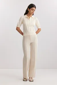 Model wearing a cream short-sleeved polo neck knit sweater with vertical texture