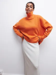 Vue détaillée d'un pull à col roulé orange oversize avec une texture en maille côtelée.