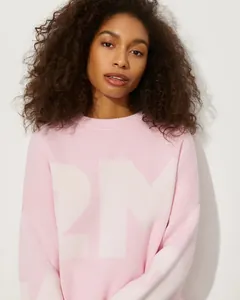 Nahaufnahme eines rosa lockeren Strickpullovers mit weißer Buchstabengrafik am Modell