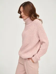 Close-up side view of a cozy women's pink chunky knit turtleneck oversized sweater