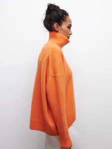 Vue latérale d'un pull orange oversize à col roulé avec une texture tricotée