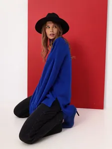 Stylish royal blue oversized turtleneck sweater with side slits in a fashion studio setting.
