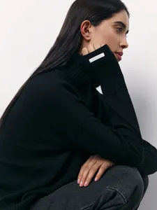 Side profile of woman in elegant black turtleneck sweater with cuff label detail