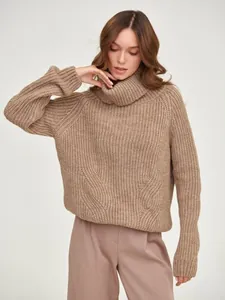 Detailed texture of women's oversized turtleneck sweater in warm beige knit
