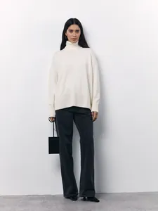 Cozy cream-colored oversized turtleneck sweater for women in a minimalist studio setting
