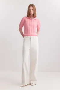 Full view of women's pink short sleeve polo knit sweater with white wide-leg pants