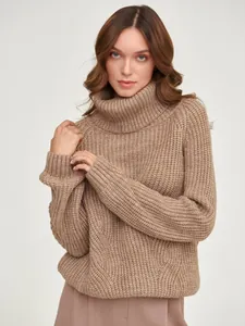 Close-up of thick beige turtleneck knitted sweater showing chunky cable-knit texture.