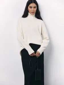 Woman in elegant off-white oversized turtleneck sweater with a long black pencil skirt