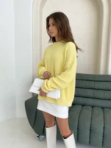 Close-up of a bright yellow loose knit sweater featuring a soft round neckline