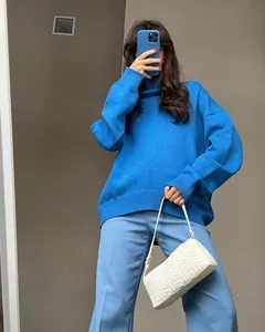 Vibrant blue thick turtleneck knitted sweater styled with a chic white shoulder bag