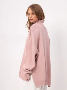 Detailed view of the pink oversized turtleneck knit sweater with side slits