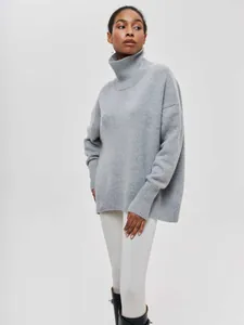 Détail d'un pull à col roulé gris surdimensionné pour femme au style minimaliste et douillet
