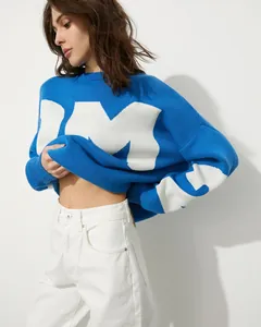 Seitenansicht einer Frau in einem blauen Oversize-Rundhalspullover mit weißen Buchstaben.
