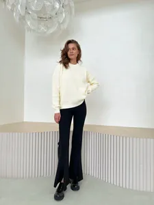 Full-length view of a model in a loose cream knitted sweater and black flare pants