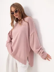 Detailed side profile of a stylish pink oversized turtleneck knit sweater worn by a model